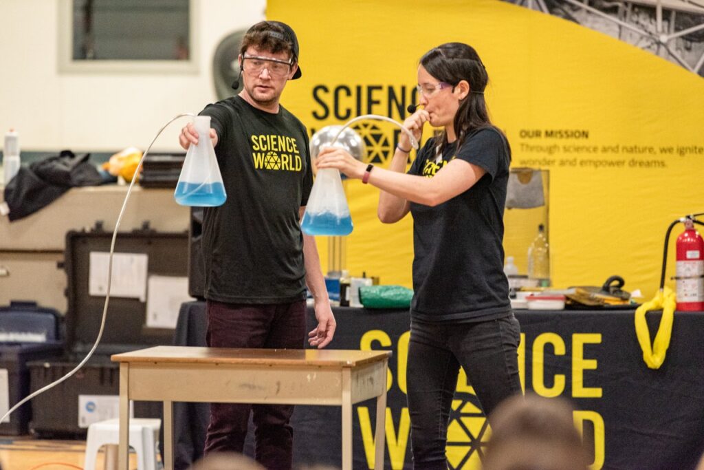 Two On the Road Science Facilitators holding beakers with blue fluid