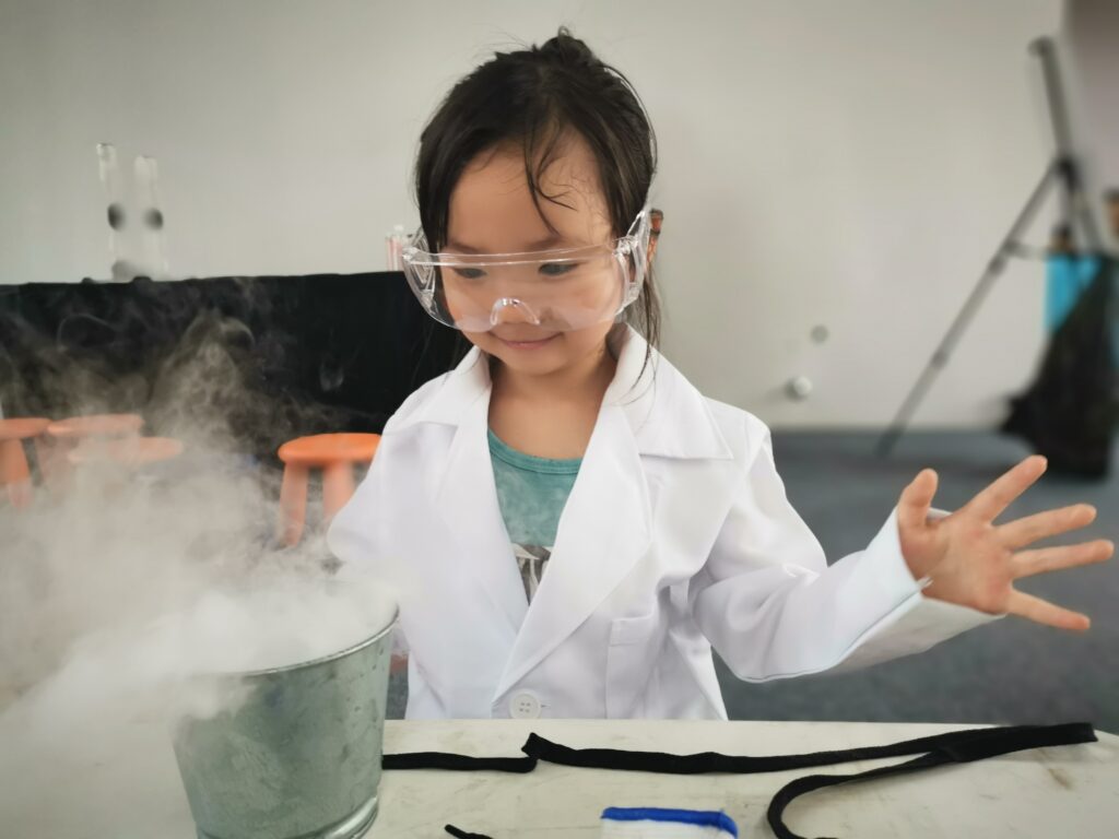 Happy young girl is looking at a smoking beaker in a chemistry environment.
