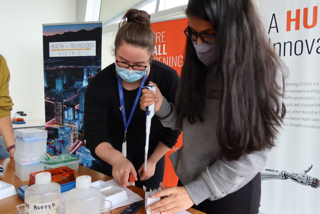 Olivia Lim helps a student in Science World's program for teens, Future Science Leaders