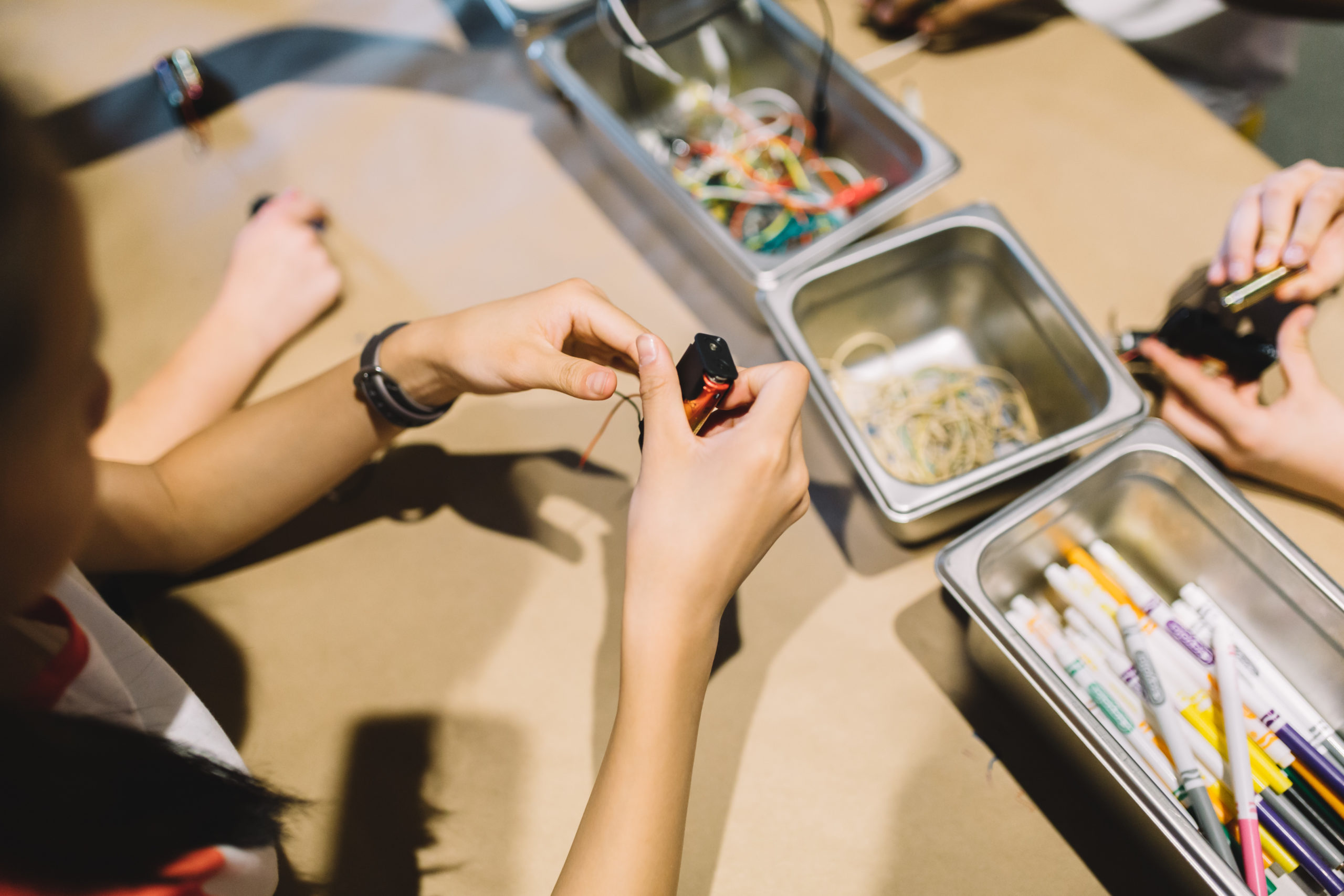 A child's hands with a battery in a workshop on the value of tinkering